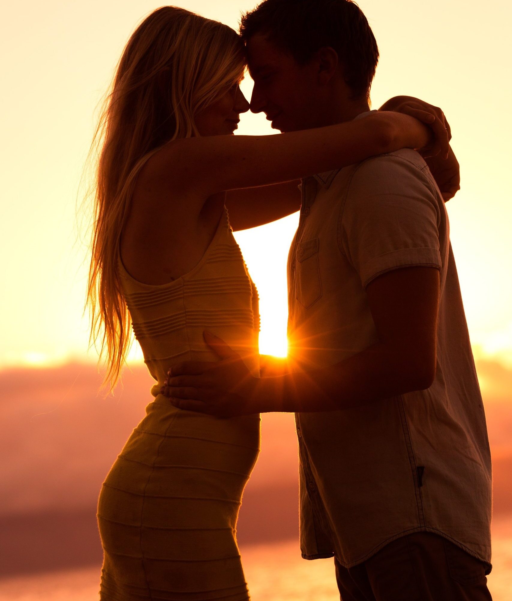 silhouette-of-romantic-couple-kissing-at-sunset-PCNULQ9